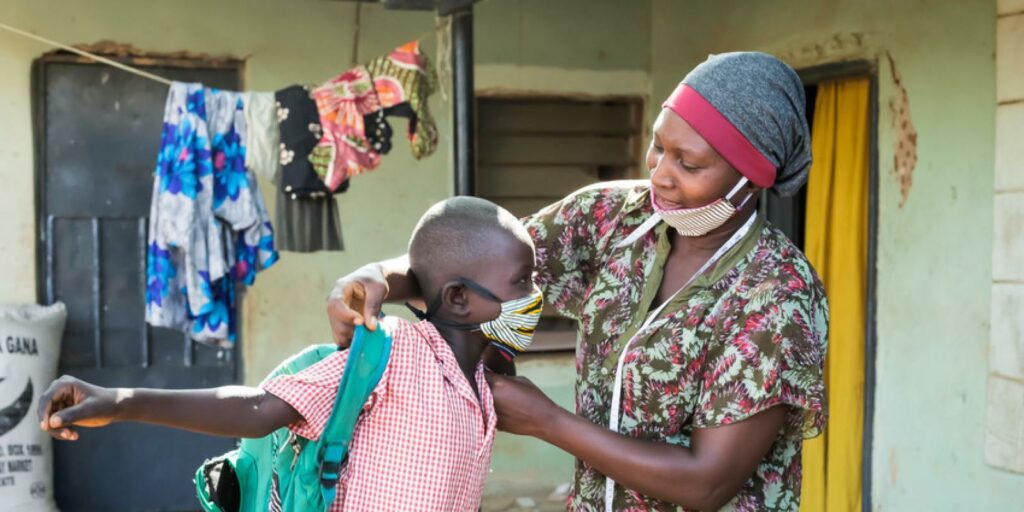 Mumagkur Hamidu helping a child with a homemade mask