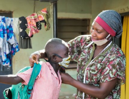 Mumagkur Hamidu helping a child with a homemade mask