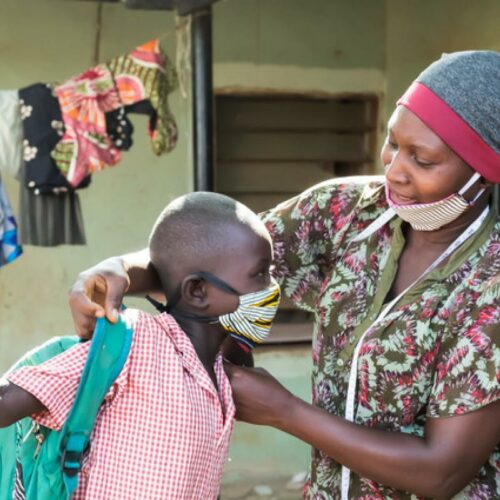 Mumagkur Hamidu helping a child with a homemade mask