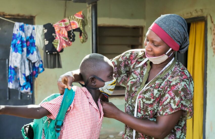 Mumagkur Hamidu helping a child with a homemade mask